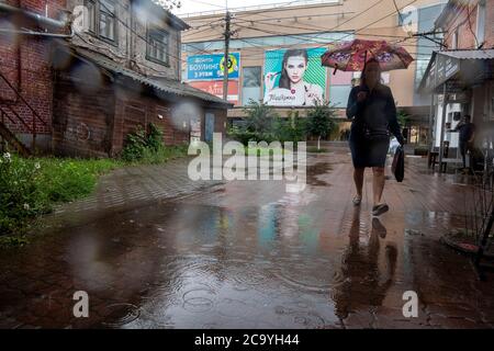 Rjasan, Russland. 2. August 2020 EINE Frau unter einem Regenschirm läuft bei starkem Regen in der Innenstadt von Rjasan, Russland, entlang einer Straße Stockfoto