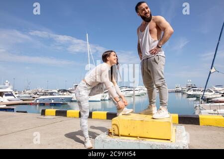 Athletische kaukasischen Paar in sportlicher Kleidung, Ausruhen nach Laufen am Strand Pier im städtischen Bereich. Stockfoto