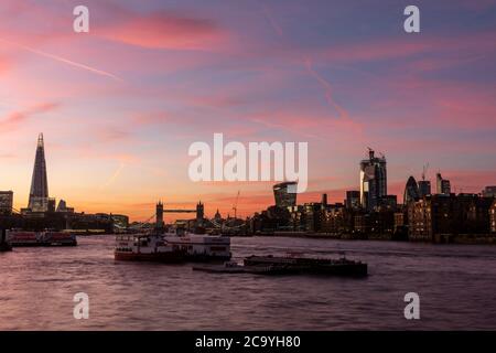 Blick von Rotherhithe nach Westen entlang der Themse mit der beleuchteten Tower Bridge und dem Eastern Cluster of the City in Silhouette. Tower Bridge, Lon Stockfoto