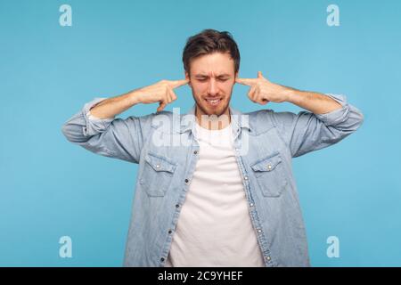 Wollen Sie nicht zuhören! Porträt des Mannes in Arbeiter-Denim-Shirt Ohren schließen und grimacing unzufrieden, irritiert durch Lärm, schwer zu hören ärgerlich soun Stockfoto