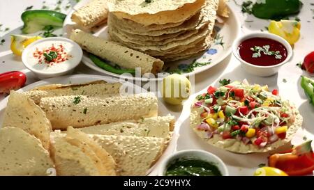 Indische Snacks, frittierte oder geröstete Mung/Urad dal Cracker oder Papad, die eine Beilage zum Mittag- und Abendessen ist. Serviert in einem Rohrkorb / Teller Stockfoto