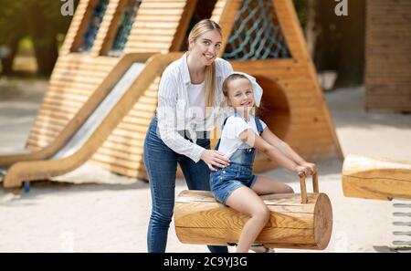 Mutter Schiebt Kleine Tochter Auf Swing Verbringen Zeit Auf Spielplatz Stockfoto