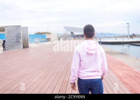 Junger Teenager, der auf der Promenade läuft und dabei die Kamera anschaut Stockfoto