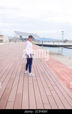 Junger Teenager, der auf der Promenade läuft und dabei die Kamera anschaut Stockfoto