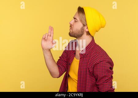 Gefährlicher Hooligan Hipster Mann in Beanie Hut und kariertes Hemd zeigt nach oben Fingerpistole, weht Rauch nach Schuss, drohen mit Waffe zu töten ges Stockfoto