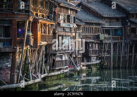 Feng Huang, China - August 2019 : Feng Huang, China - August 2019 : Chinesischer Mann mittleren Alters, der auf dem Balkon eines alten historischen Diaoji aus Holz steht Stockfoto