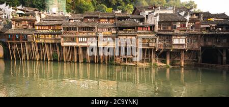 Feng Huang, China - August 2019 : Panoramablick auf die alten historischen Diaojiao-Holzhäuser am Ufer des Flusses Tuo, die durch den Zentr Stockfoto