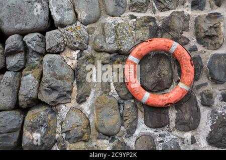 Verwitterter Rettungsring an der Hafenmauer in Clovelly, Devon UK Stockfoto