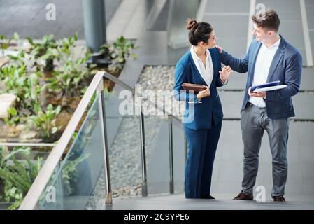 Junger Geschäftsmann berührt die Schulter seiner Kollegin, um sie vor einem wichtigen Treffen zu unterstützen Stockfoto
