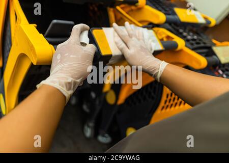 Hände von Menschen mit Sprühen Alkohol antiseptisch, Desinfektionsspray, Reinigung auf Warenkorb, Trolley Griff, Schutz während Coronavirus Pandemie, C Stockfoto