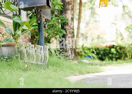 Leere Milchflaschen aus Glas auf dem Rasen neben dem Briefkasten Stockfoto