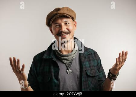 Kaukasischer Reparaturmann mit Schnurrhaaren mit zufrieden lächelndem Ausdruck sagt der Kamera, dass alle Varianten und Autoteile verfügbar sind und der Service funktioniert Stockfoto