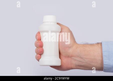 Männliche Hand hält Plastikflasche mit Pillen. Speicherplatz kopieren. Vorlage. Modell Stockfoto