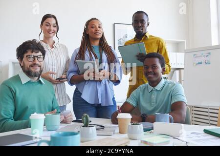 Porträt eines multiethnischen Geschäftsteams, das während des Meetings im Konferenzraum posiert und dabei die Kamera anschaut Stockfoto