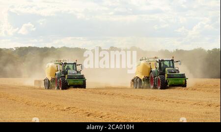 Zwei Traktoren mit Heupressen auf einem Feld. Viel Hadham, Hertfordshire. VEREINIGTES KÖNIGREICH. Stockfoto