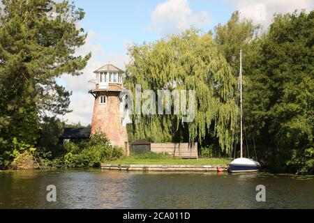 Yacht liegt neben einer alten, umgebauten Windmühle, mit einem weinenden Weidenbaum, Norfolk Broads, England Stockfoto