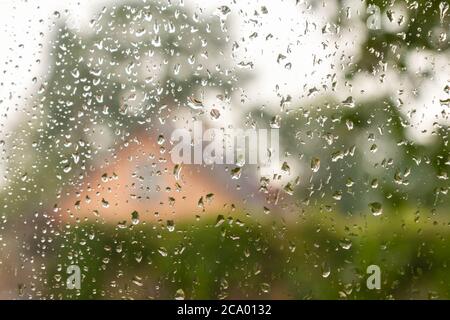 Wassertropfen auf dem Fenster. Herbst ländliche Landschaft durch Regentropfen auf dem Fensterglas. Regentropfen auf das Fensterglas auf verschwommenem Hintergrund. Nassglas Stockfoto