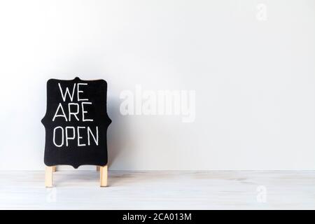 Wir sind offen - Worte mit weißer Kreide auf Tafel geschrieben. Kreidetafel mit Handschrift Text SIND WIR OFFEN. Schild öffnen. Speicherplatz kopieren. Back to Business Konz Stockfoto