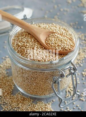 Trocknen Sie weiße Quinoa-Samen in einem Glas auf einem grauen Tisch aus nächster Nähe Stockfoto