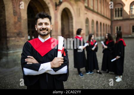 Nahaufnahme von einem lächelnden graduate lächelnd mit ihren Freunden im Hintergrund vor der Universität Stockfoto