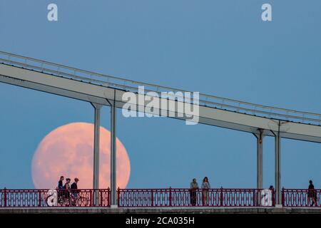Silhouetten von Menschen auf der Brücke vor dem Hintergrund des aufgehenden Vollmondes, Kiew, Ukraine Stockfoto