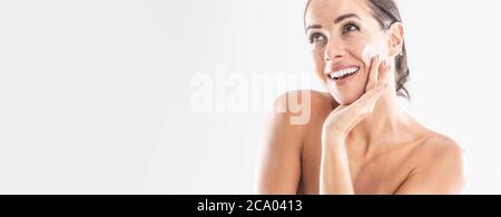 Schöne junge Frau Anwendung Creme auf ihr Gesicht isoliert auf weiß. Hautpflege Spa Wellness und Kosmetik-Konzept. Stockfoto