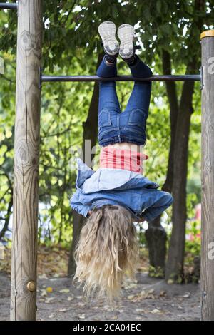 Mädchen (10) hängt kopfüber auf horizontaler Stange, Kiel, Schleswig-Holstein, Deutschland Stockfoto