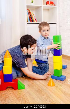 Mitreißende Kinder spielen mit Konstruktor auf dem Boden zu Hause Stockfoto