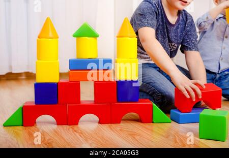 Kinder spielen mit Konstruktor auf dem Boden zu Hause. Nahaufnahme der Hände Stockfoto