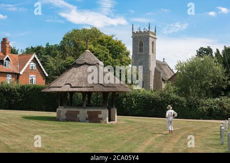 Woodbastwick Norfolk, Blick über das Dorfgrün in Woodbastwick in Richtung der reetgedeckten Pfarrkirche der Heiligen Fabian und Sebastian, Norfolk, Großbritannien Stockfoto