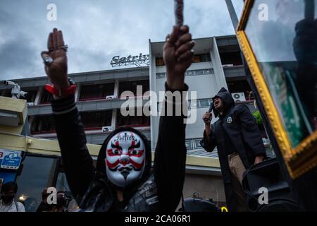 Bangkok, Thailand. August 2020. Ein prodemokratischer Protestler, der als Zauberer gekleidet ist, hält eine Rede, während ein anderer, der eine Maske trägt, den dreifingerigen Gruß - ein Symbol, das von thailändischen Protestierenden aus den Hungerspielen übernommen wurde - gegenüber dem Democracy Monument während eines Harry Potter-Protestes in Bangkok, Thailand, Montag, 3. August 2020, hält. Der prodemokratische Protest trug den Titel "Gießen des Patronus-Charms zum Schutz der Demokratie", Teil einer Reihe von Protesten in den letzten Wochen. Die Proteste sind seit Februar wegen des COVID-19 Ausbruchs eingestellt, aber Thailand hat keine neuen lokalen Transmit registriert Stockfoto