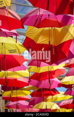 Eine große Sammlung von roten und gelben Regenschirme hängen in Camden Markt schaffen ein angenehmes Muster. London, England, Großbritannien Stockfoto