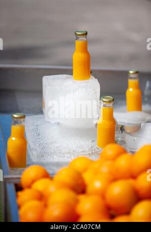 Frisch abgefüllter Orangensaft auf einem großen Eisblock, Camden High Street, London, England Stockfoto