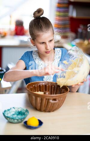 Junges Mädchen macht, einfach zuzubereiten und gesund, hausgemachte Osterkuchen. Sie setzt den Teig in eine alte Keramikbackform. Stockfoto