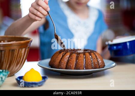 Junges Mädchen macht, einfach zuzubereiten und gesund, hausgemachte Osterkuchen - während des Aufenthalts zu Hause. Sie schmückt den Kuchen mit dunkler Schokolade. Stockfoto