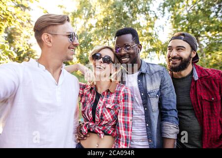 Gruppe von multiethnischen Studenten in verschiedenen Freizeitkleidung gekleidet Spaziergang im Park, Gefühl von Freude und Glück. Freundschaft, Integration und multikulturelle Kon Stockfoto