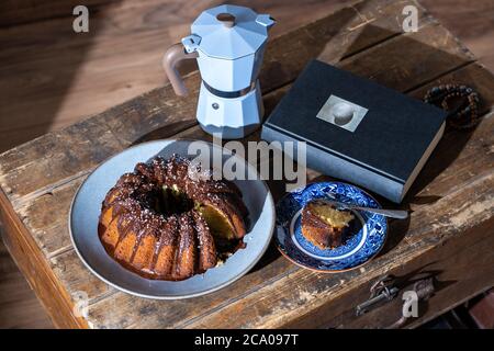 Osterkuchen, gutes Buch und heißer Kaffee auf altem, dunklem Holztisch - schöner Nachmittag während des Aufenthalts zu Hause. Stockfoto