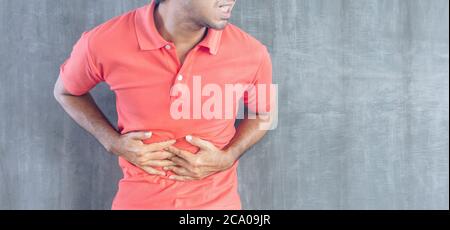 Junge asiatische Mann mit einem Magen Schmerzen auf Zement Wand Hintergrund mit Kopierer Raum, Probleme und Konzepte der Gesundheitsversorgung Stockfoto