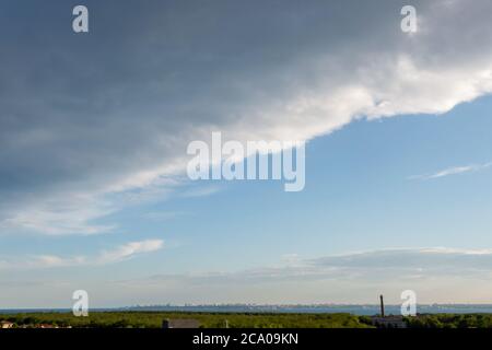Wunderschöne dramatische Wolken über dem Meer. Dächer von Häusern an der Küste. Stockfoto