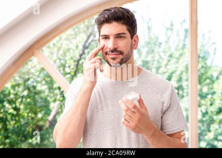 Schuss von lächelnden Mann Anwendung Feuchtigkeitscreme auf sein Gesicht. Stockfoto
