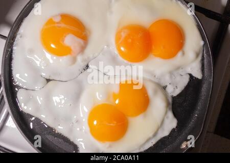Einfache rustikale Spiegeleier in einer Bratpfanne Draufsicht. Eier mit zwei Eigelb. Blick durch Dampf. Stockfoto