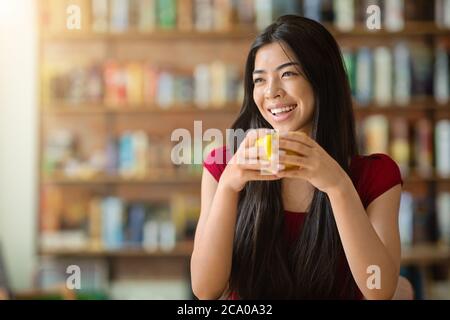 Kaffeepause. Happy Asian Girl Genießen Heiße Getränke Im Café, Holding Cup Stockfoto