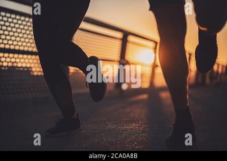 Körperteil Silhouetten von Paar, das in der Stadt im Sonnenuntergang joggt. Stockfoto