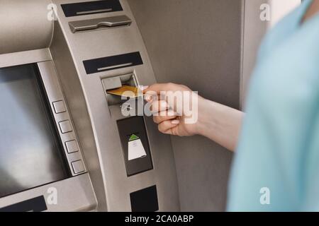 Nahaufnahme der weiblichen Hand, die die Kreditkarte in den Geldautomaten einführt Stockfoto