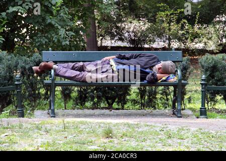 Obdachloser schläft auf einer Bank in Krakau, Polen AUGUST-30-2018. Stockfoto
