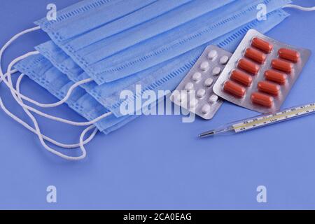 Schützende medizinische Maske, Pillen, Thermometer auf blauem Hintergrund, Corona-Virus-Schutz,Konzept einer Prävention und Behandlung Coronavirus, covid19 PR Stockfoto