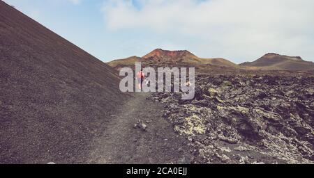 Wanderweg auf dem Vulkan Caldera de la Rilla im Naturpark Los Volcanes, mit einem Wanderer und Montana de Santa Catalina in der Ferne. Stockfoto