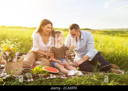 Kleine Tochter füttert ihren Vater mit Traube Stockfoto