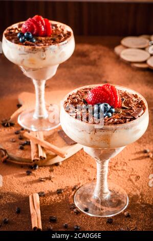 italienisches Dessert Tiramisu mit Erdbeere in einem eleganten Cocktailglas, das Konzept des süßen Lebens, Luxus, leckeres Essen Stockfoto