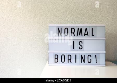Normal ist langweilig in Leuchtkasten Hausdekoration, Motivationszeichen Retro-Haus, Raum für Text geschrieben Stockfoto